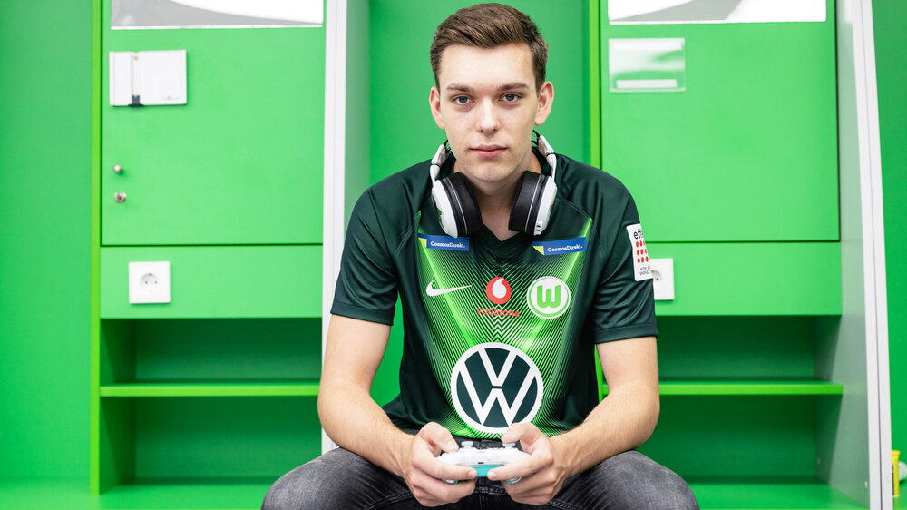 E-Sportler Benedikt Bauer mit einem Gamepad in der Hand in der Umkleidekabine.