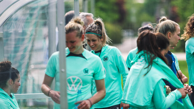 Kathrin Hendrich und die anderen Spielerinnen vom VfL Wolfsburg halten sich vor der Trainerbank auf.
