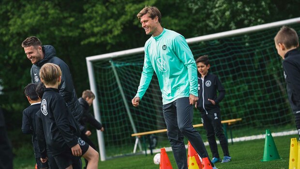 VfL-Wolfsburg-Spieler Mattias Svanberg und Kevin Behrens lachen während sie mit den Kindern des Nordsteimker Nachwuchs trainieren.