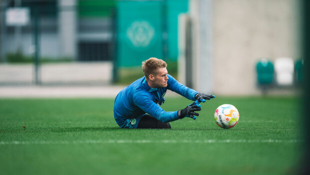 Der VfL-Wolfsburg-Torwart Philipp Schulze pariert einen flach-geschossenen Ball.