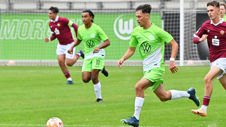 Ein Spieler der U17 Mannschaft des VfL Wolfsburg rennt mit dem Ball am Fuß über den Platz und wird von einem gegnerischen Spieler verfolgt.
