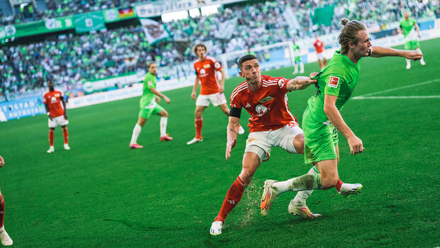 Ein Gegenspieler zieht VfL-Wolfsburg-Spieler Patrick Wimmer am Trikot.