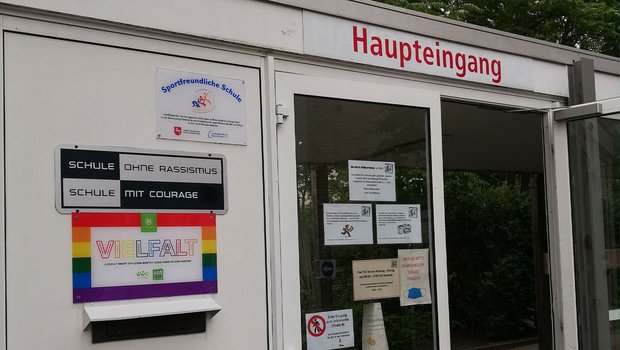 Am Schuleingang hängt ein regenbogenfarbenes Schild mit der Aufschrift "Vielfalt" vom VfL Wolfsburg.
