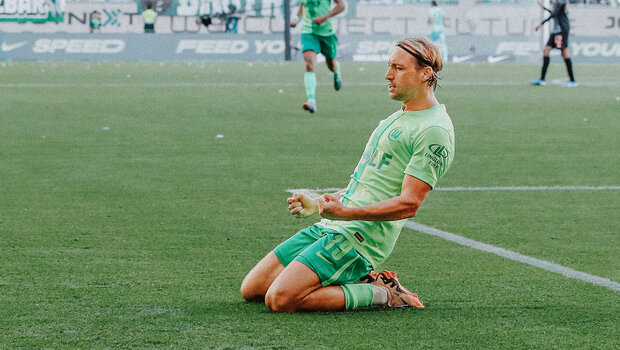 VfL-Wolfsburg-Spieler Lovor Majer rutscht auf den Knien über den Rasen und ballt dabei beide Fäuste.