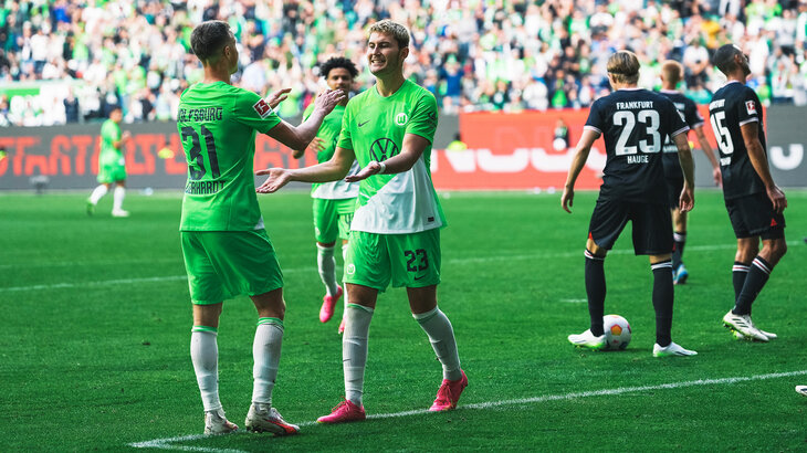 Die Spieler des VfL Wolfsburg klatschen sich jubelnd auf dem Platz ab.