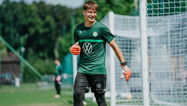 Der Torwart der U19 des VfL Wolfsburg lacht auf dem Trainingsplatz.