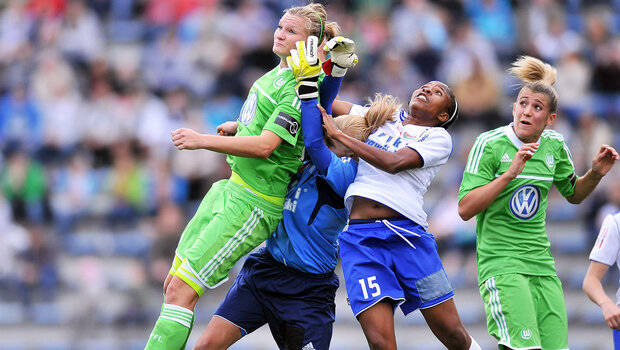 Zwei VfL Wolfsburg Spielerinnen kämpfen auf dem Platz gegen zwei Gegnerinnen um den Ball.