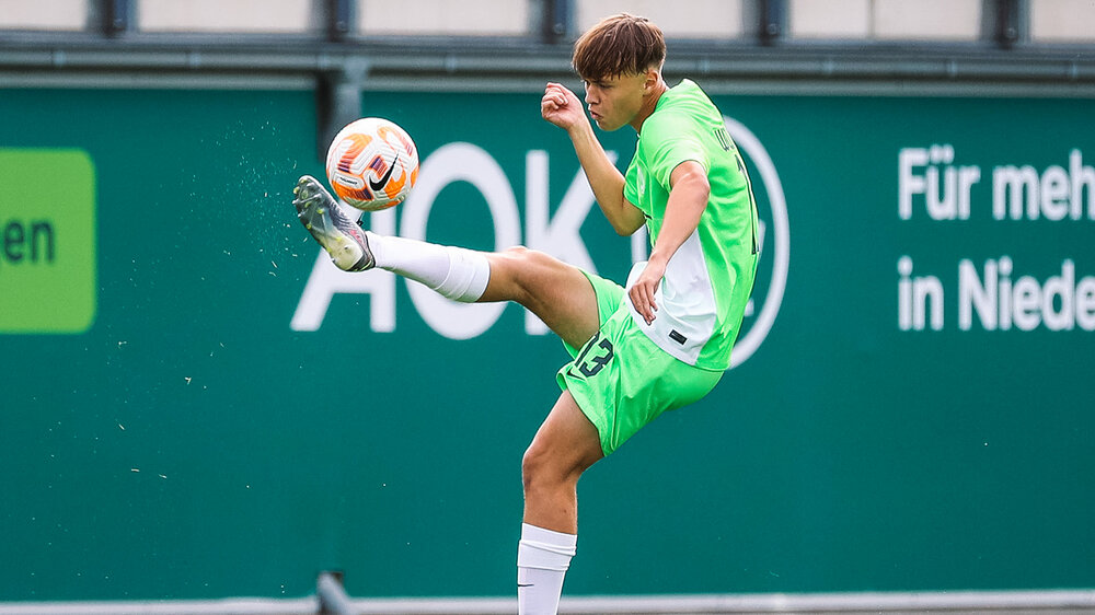 Ein Spieler der U17 des VfL Wolfsburg nimmt den Ball mit dem Fuß in der Luft an.