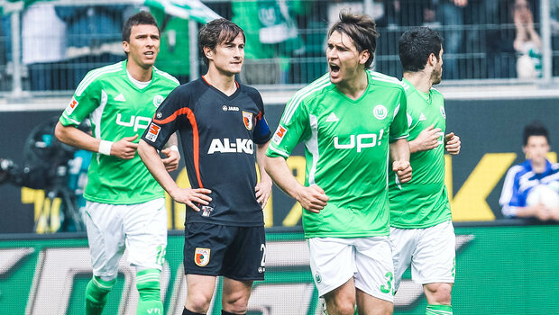 Historisches Foto von VfL Wolfsburg Spielern, die sich in einem Spiel gegen Augsburg beim Schiedsrichter beschweren.