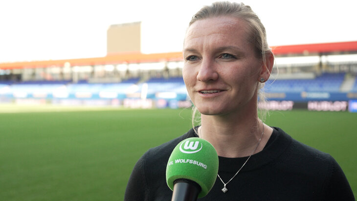 Alexandra Popp vom VfL Wolfsburg steht im Stadion. Vor ihr wird ein Mikro gehalten.