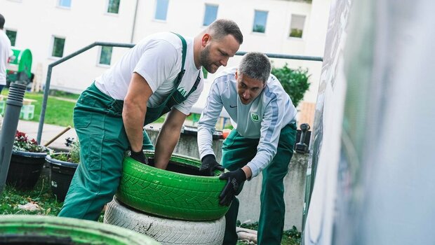 VfL Wolfsburg Mitarbeiter stapeln grün-weiße Reifen am "Wir-für euch"-Tag.