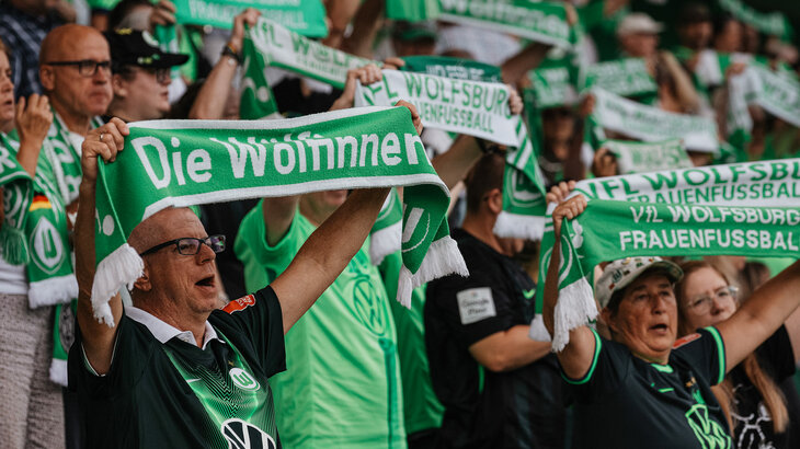 Fans der Frauenmannschaft des VfL Wolfsburg halten grün-weiße Fanschals in die Höhe.