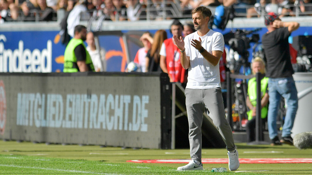 Eintracht Frankfurt Trainer Arnautis steht in die Hände klatschend am Spielfeldrand.