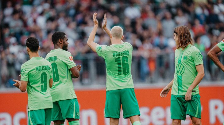 Die VfL-Wolfsburg-Spieler Jakub Kaminski und Ridle Baku winken in Richtung der Fans.