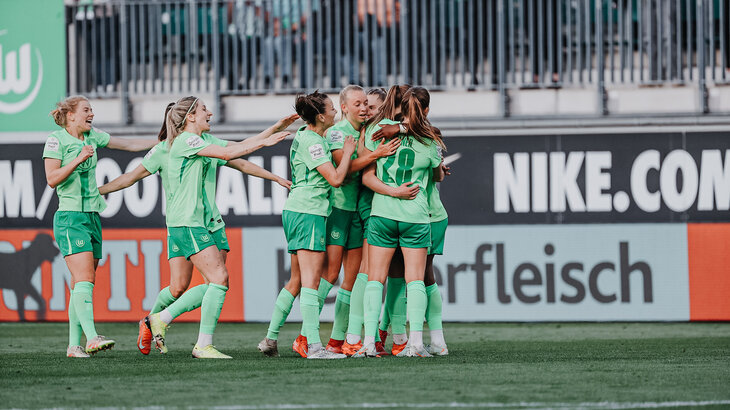Die Spielerinnen vom VfL Wolfsburg freuen und umarmen sich.
