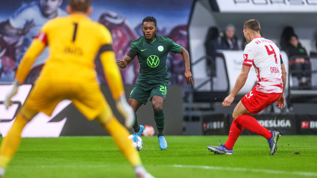 VfL Wolfsburg Spieler Baku marschiert mit dem Ball am Fuß an einem Gegenspieler aus Leipzig vorbei.