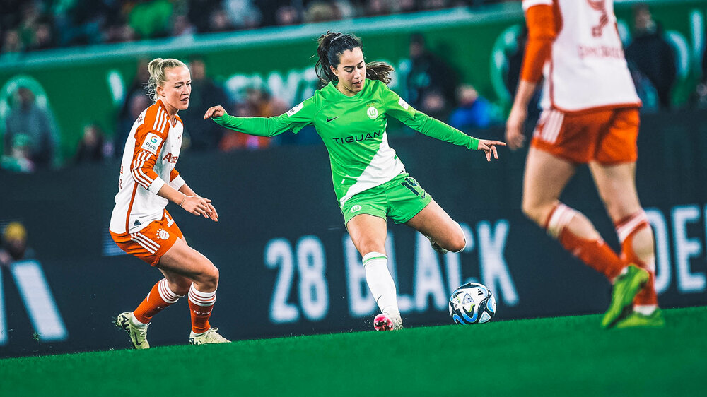 VfL Wolfsburg Spielerin Nuria Blanco setzt sich mit dem Ball am Fuß gegen eine Gegenspielerin aus München durch.