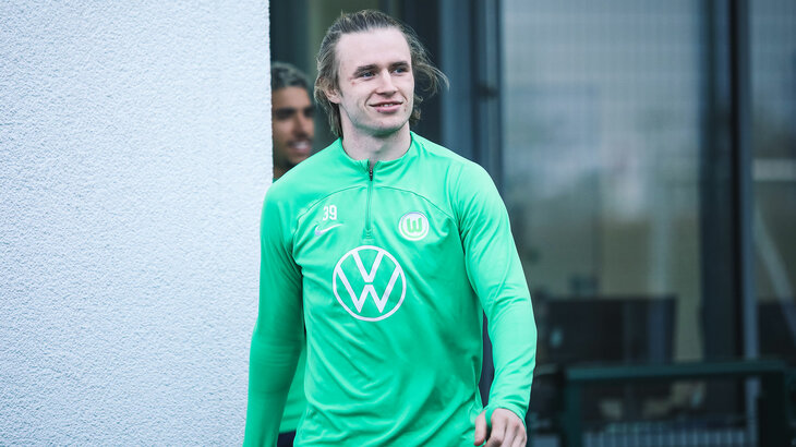 VfL-Wolfsburg-Spieler Patrick Wimmer kommt aus dem Trainingsgebäude und lächelt.