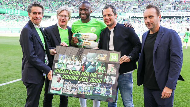 Josuha Guilavogui hält zusammen mit den VfL-Wolfsburg-Geschäftsführern seine Abschiedsgrafik in den Händen.