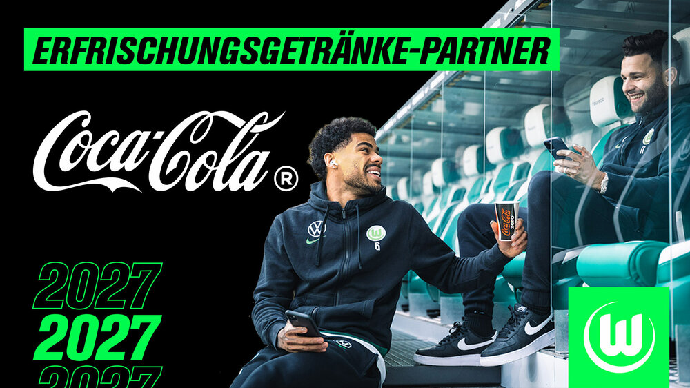 VfL-Wolfsburg-Spieler Paulo Otavio hält Renato Steffen einen Coca-Cola-Becher entgegen. Links steht der Schriftzug "Erfrischungsgetränke Partner" und "Coca Cola".