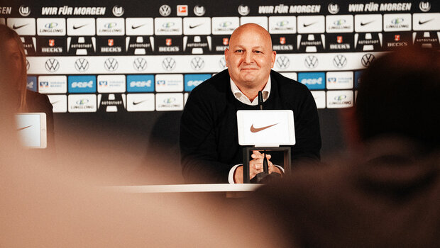 VfL-Wolfsburg-Geschäftsführer Peter Christiansen sitzt auf der Pressetribüne und schaut die Journalisten an.