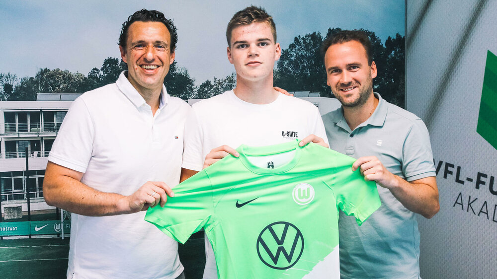 Anders Börset hält zusammen mit den Verantwortlichen ein VfL-Wolfsburg-Trikot hoch.