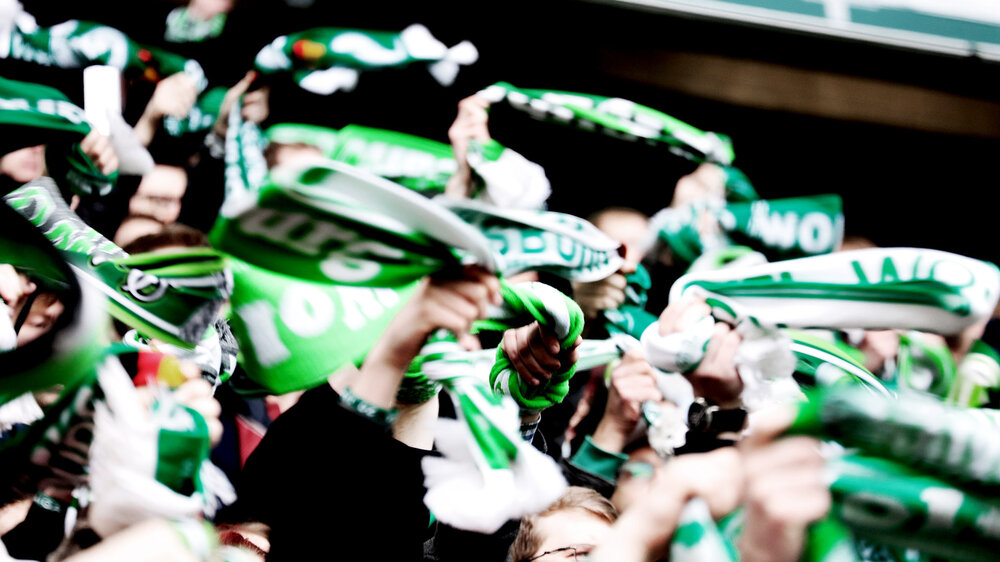 Fans des VfL Wolfsburg wedeln mit ihren Schals. 