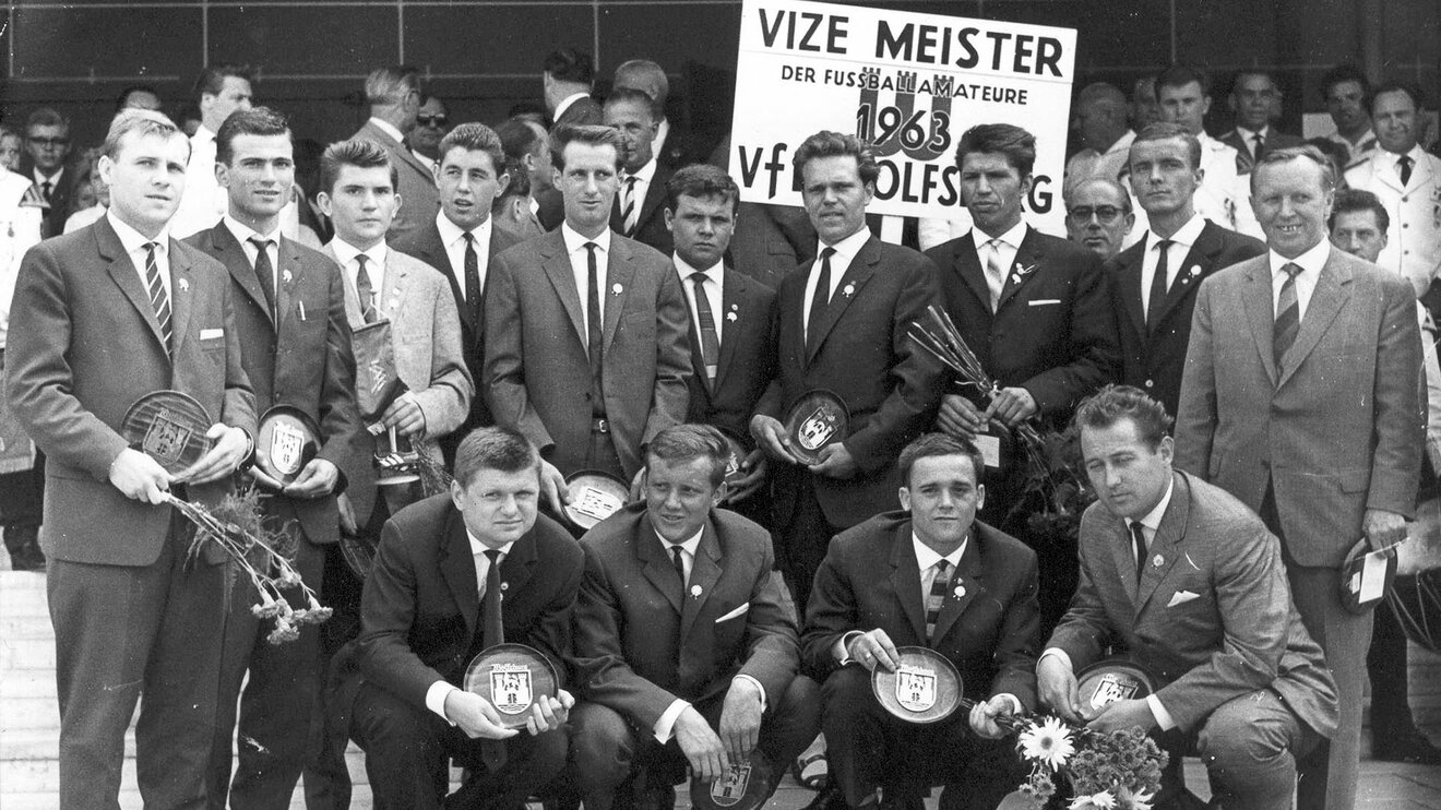 Ein historisches Bild mit Verantwortlichen vom VfL Wolfsburg und einem Vizemeister-Schild.