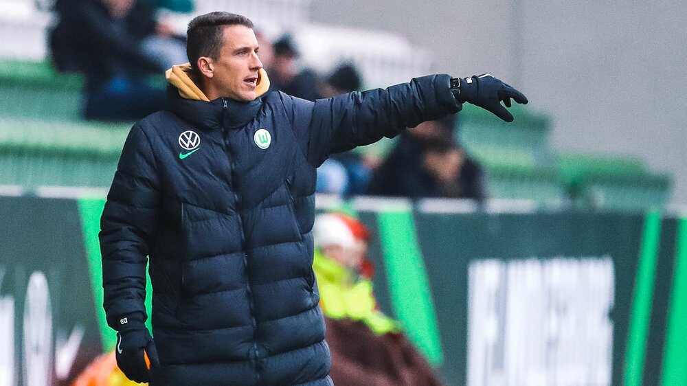 VfL-Wolfsburg-U19-Trainer Daniel Bauer streckt seinen Arm aus und gibt Anweisungen.