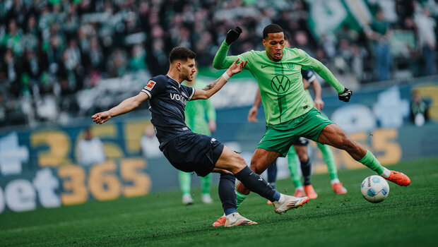 VfL-Wolfsburg-Spieler Aster Vranckx im Zweikampf um den Ball mit einem Gegenspieler.