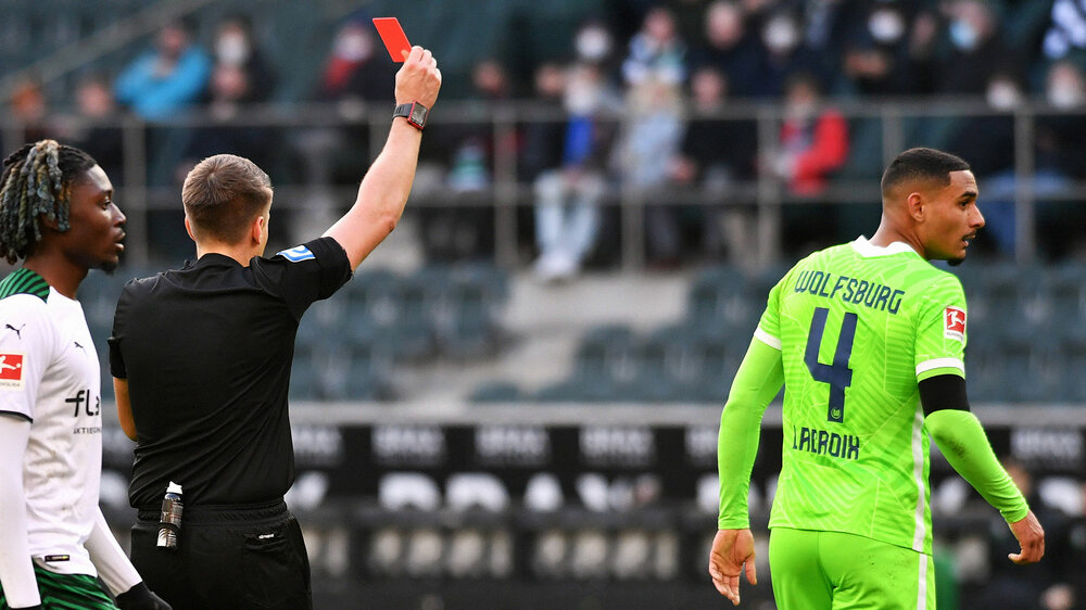 VfL-Wolfsburg-Spieler Lacroix bekommt eine rote Karte vom Schiedsrichter gezeigt.
