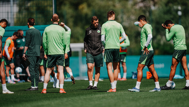 VfL Wolfsburg Co-Trainer Julian Klamt steht auf dem Trainingsplatz und um ihn herum stehen die Spieler des VfL.
