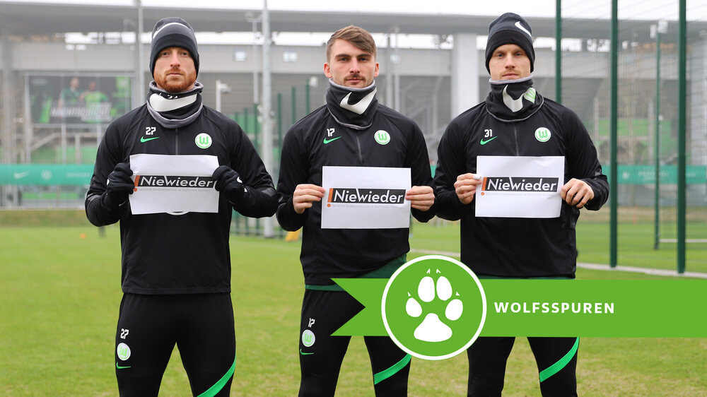 VfL-Wolfsburg-Spieler Arnold, Philipp und Gerhardt mit Schildern zur Nie-Wieder Kampagne.