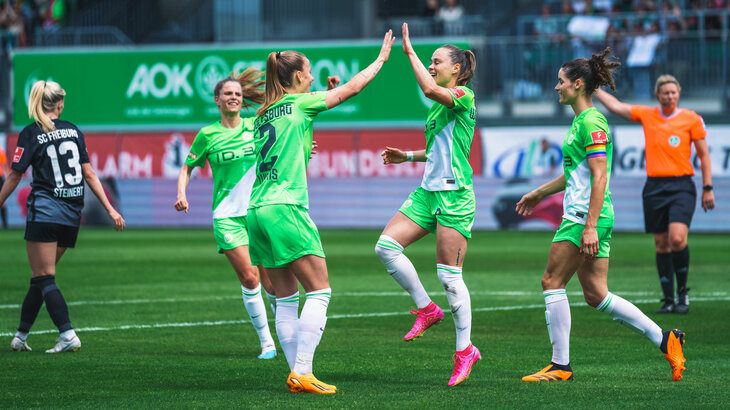 Zwei Spielerinnen des VfL Wolfsburg geben sich jubelnd ein High Five.
