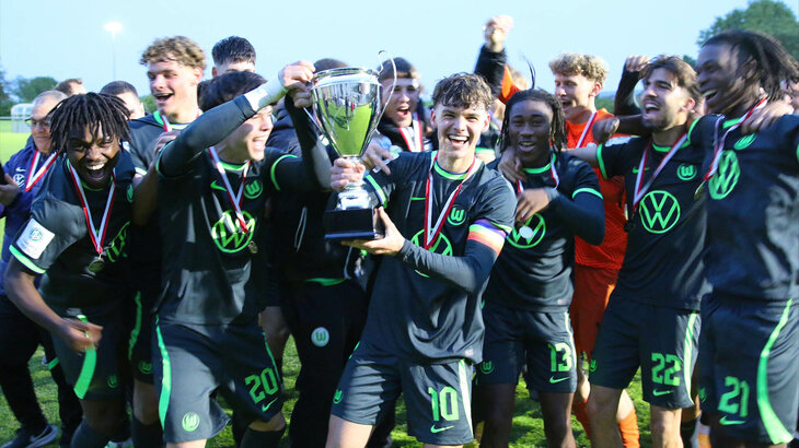 Die U19 Mannschaft des VfL Wolfsburg jubelt frenetisch mit Pokal in der Hand.