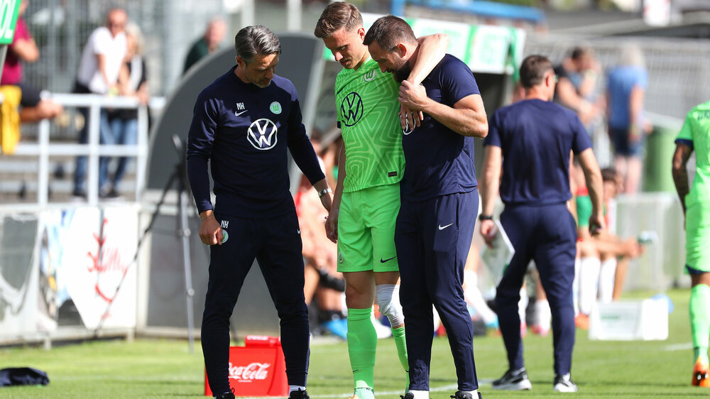 Der VfL Wolfsburg-Spieler Yannick Gerhardt wird verletzt vom Platz begleitet.