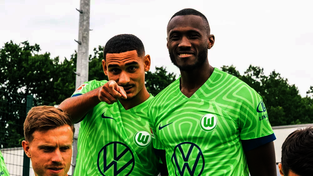 VfL-Wolfsburg-Spieler Maxcence Lacroix lacht mit seinem Mitspieler Guilavogui beim Fototermin in die Kamera.