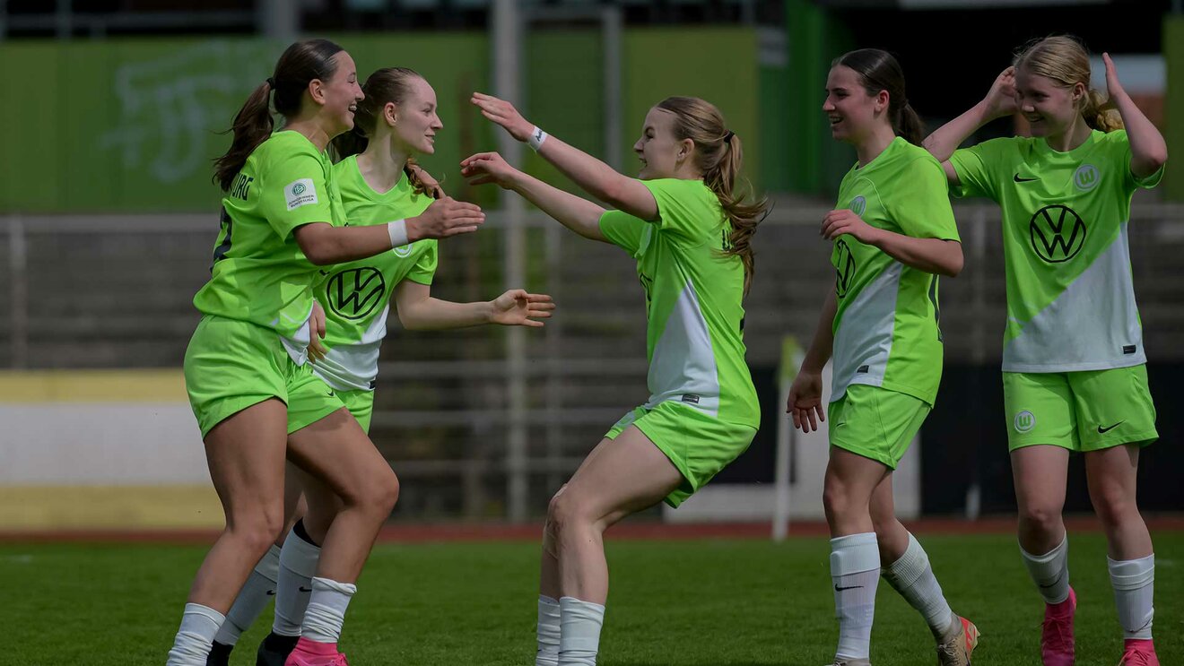 Die Nachwuchs-Spielerinnen des VfL Wolfsburg umarmen sich und bejubeln ihren Treffer. 
