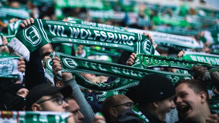 VfL-Wolfsburg-Fans halten ihre grün-weißen Fanschals in die Höhe.