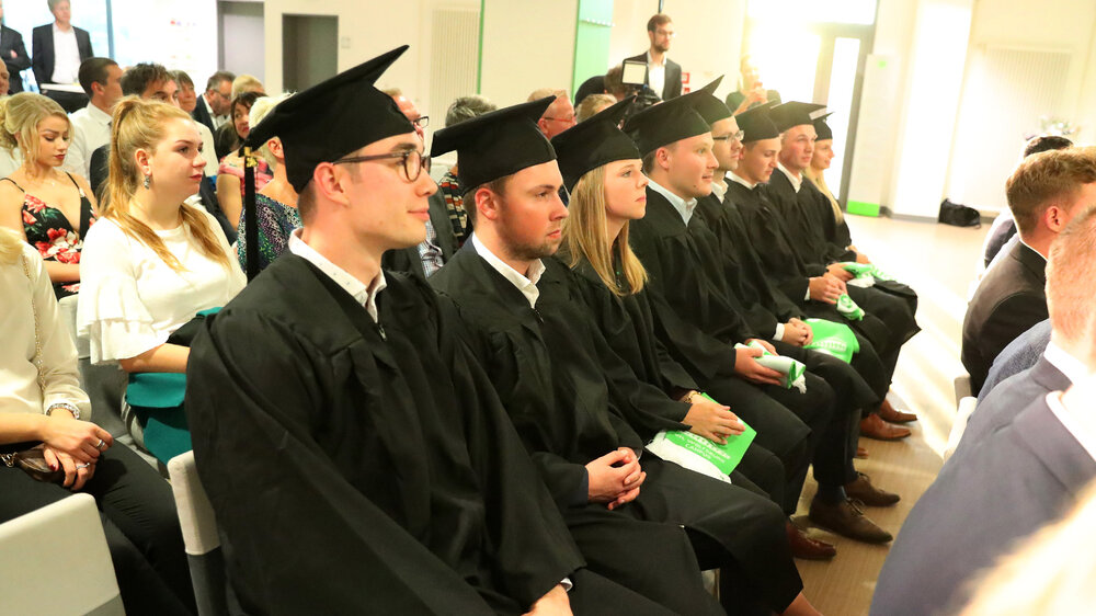 Absolventen des VfL Campus sitzen während der Abschlussfeier nebeneinander.