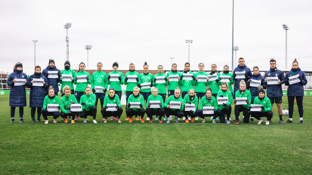 Die Frauen des VfL Wolfsburg halten gesammelt Schilder mit der Aufschrift Nie Wieder. 