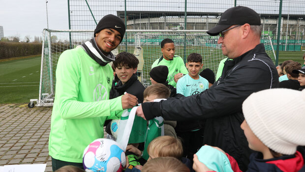 Ein Spieler des VfL Wolfsburg signiert Fanartikel.
