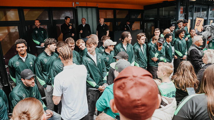 Die Spieler des VfL Wolfsburg stehen in einer Reihe vor den Fans.