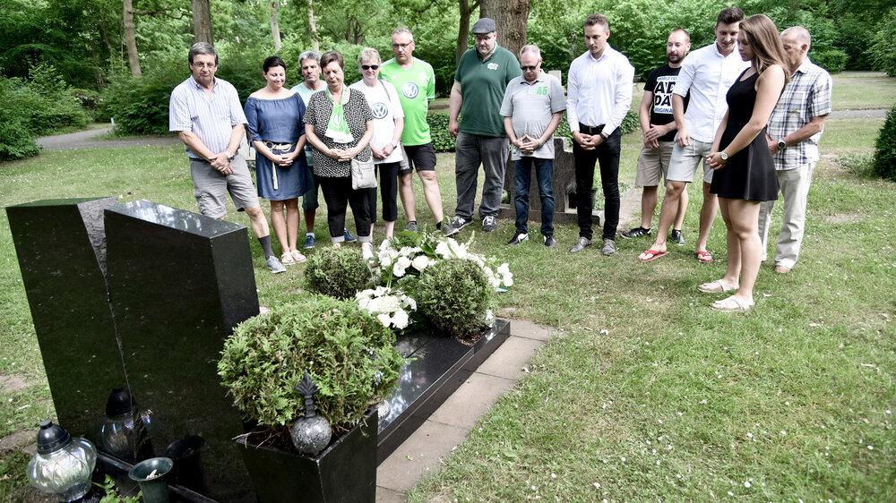 VfL Wolfsburg-Geschäftsführer Wolfgang Hotze und weitere Trauergäste stehen am Grab von Krzystof Nowak.