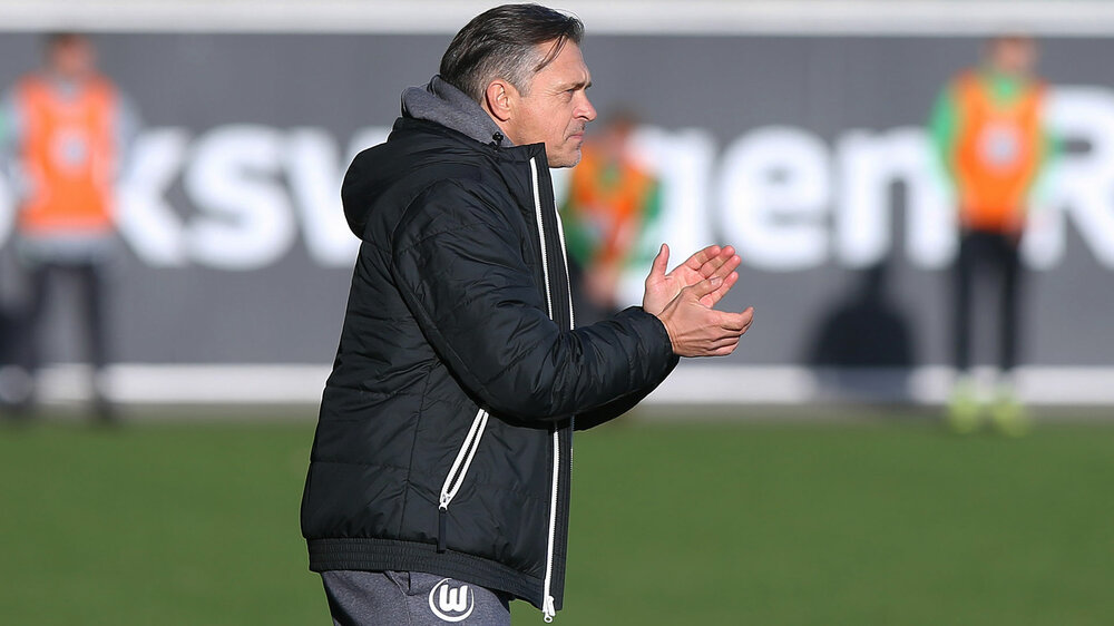 VfL Wolfsburg U19 Trainer Bürger steht am Spielfeldrand und klatscht.
