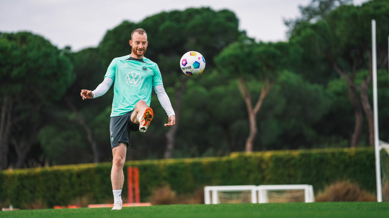 VfL-Wolfsburg-Kapitän Maximilian Arnold hält mit Freude den Ball hoch.