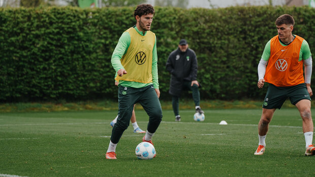 VfL Wolfsburg Spieler Jonas Wind mit dem Ball am Fuß auf dem Trainingsplatz, Kollege Joakim Maele versucht ihm den Ball abzunehmen.