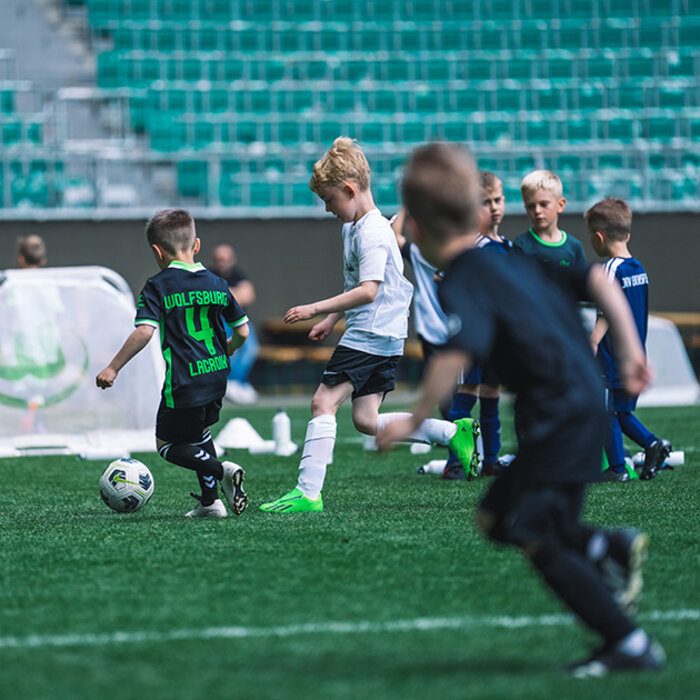 Kinder spielen Fußball in der Volkswagenarena des VfL Wolfsburg.