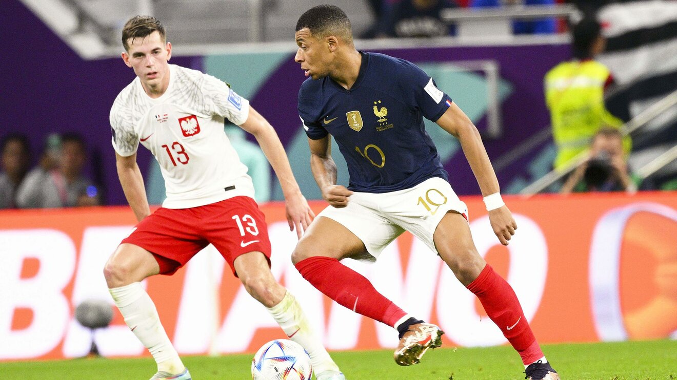 VfL-Wolfsburg-Spieler Jakub Kaminski im Trikot der polnischen Nationalmannschaft und im Zweikampf um den Ball gegen Kylian Mbappe.