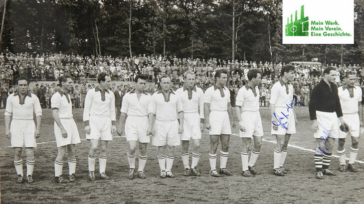 Historische Aufnahme der Mannschaft des VfL Wolfsburg, die nebeneinander auf dem Platz steht.